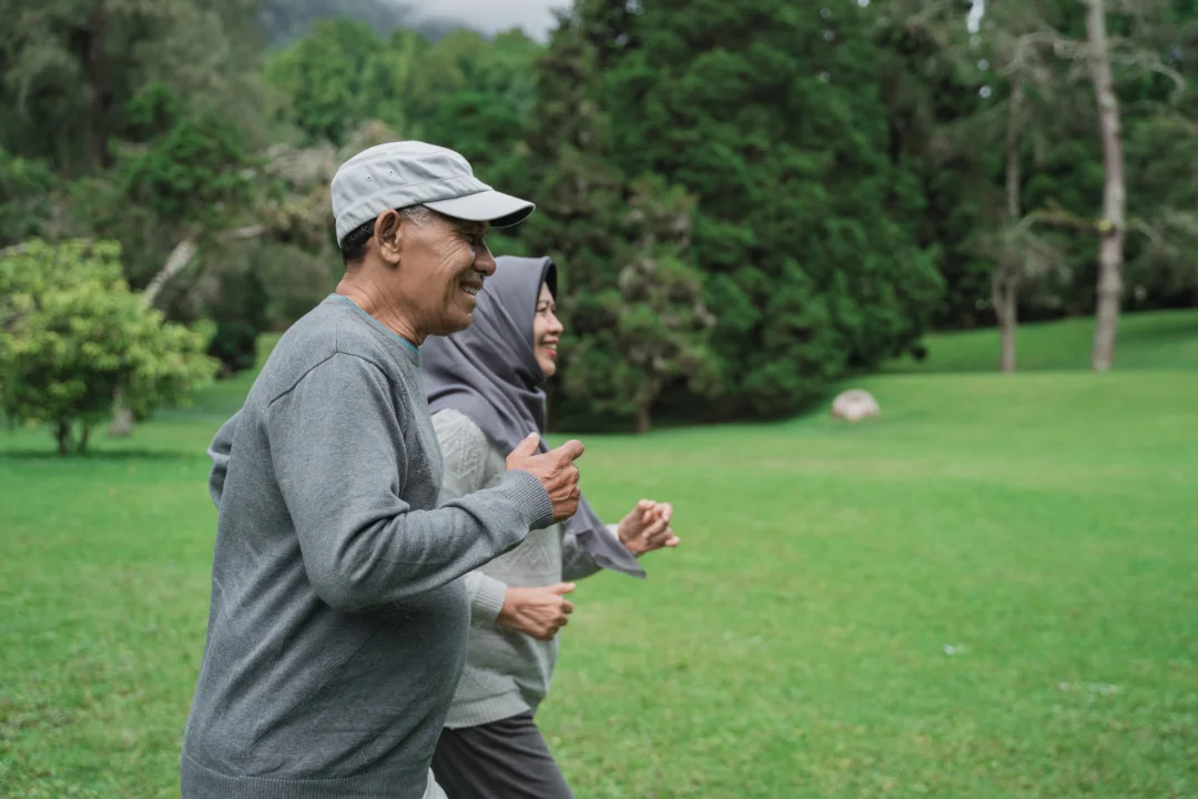Older man and woman jogging together in a park